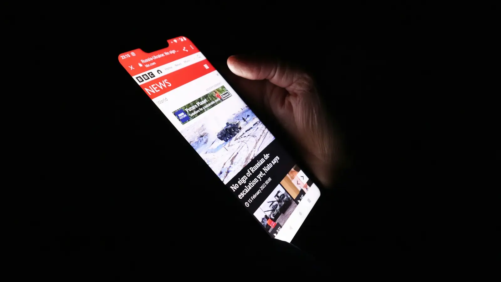 Persona sosteniendo un celular con la pantalla encendida en la oscuridad
