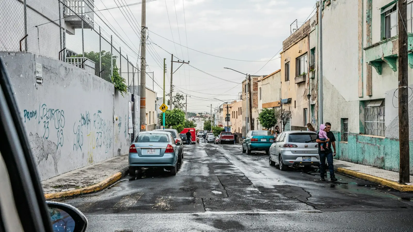 Calle de Guadalajara con autos estacionados y cables de luz, vista desde un coche